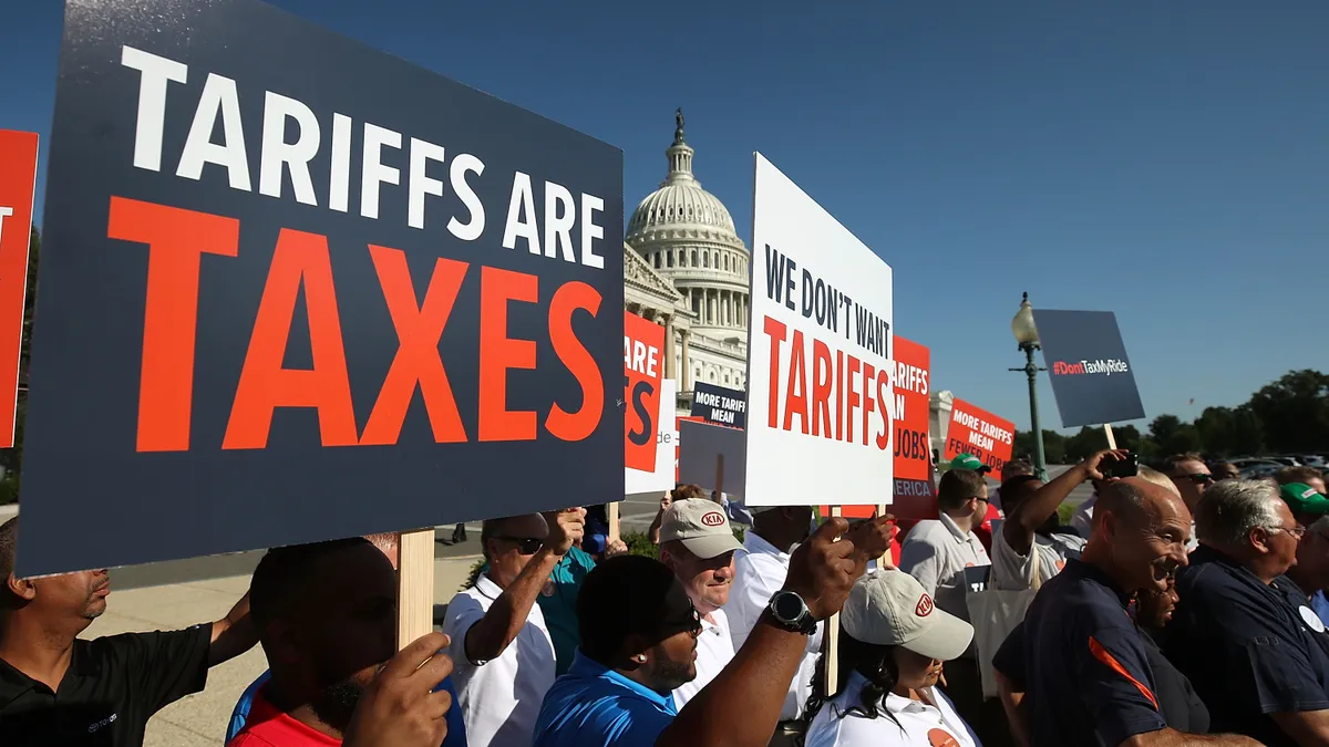 Protesters hold up signs with messages proclaiming "Tariffs are taxes" and "We don't want tariffs" in front of the U.S. Capitol