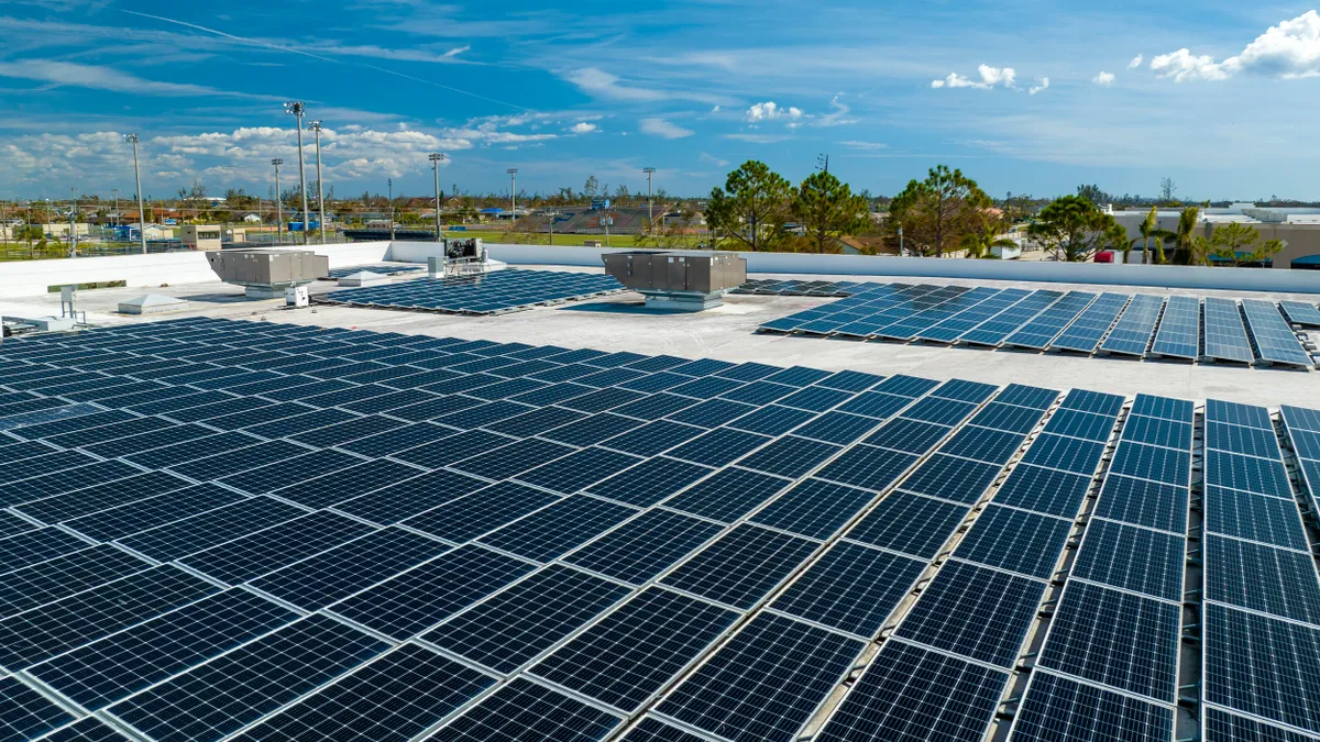 Aerial view of blue photovoltaic solar panels mounted on industrial building roof for producing clean ecological electricity.