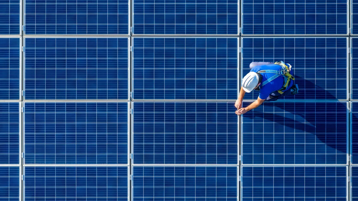 Engineer in blue suit and protective helmet installing photovoltaic panel system.