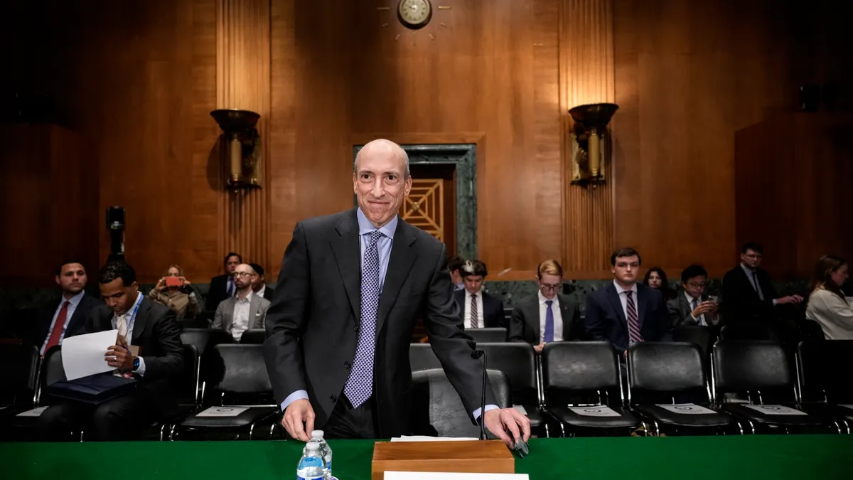 Gary Gensler smiles as he prepares to sit and testify