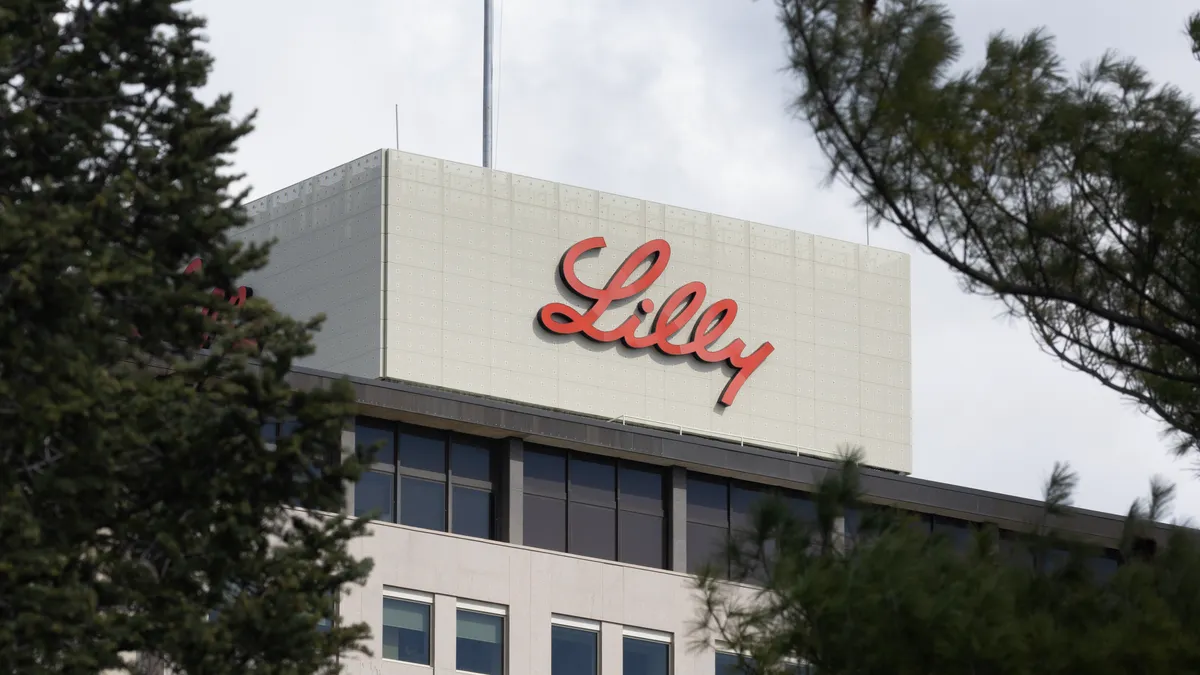 A U.S. flag flying above a building showing a sign with the word Lilly written in red.