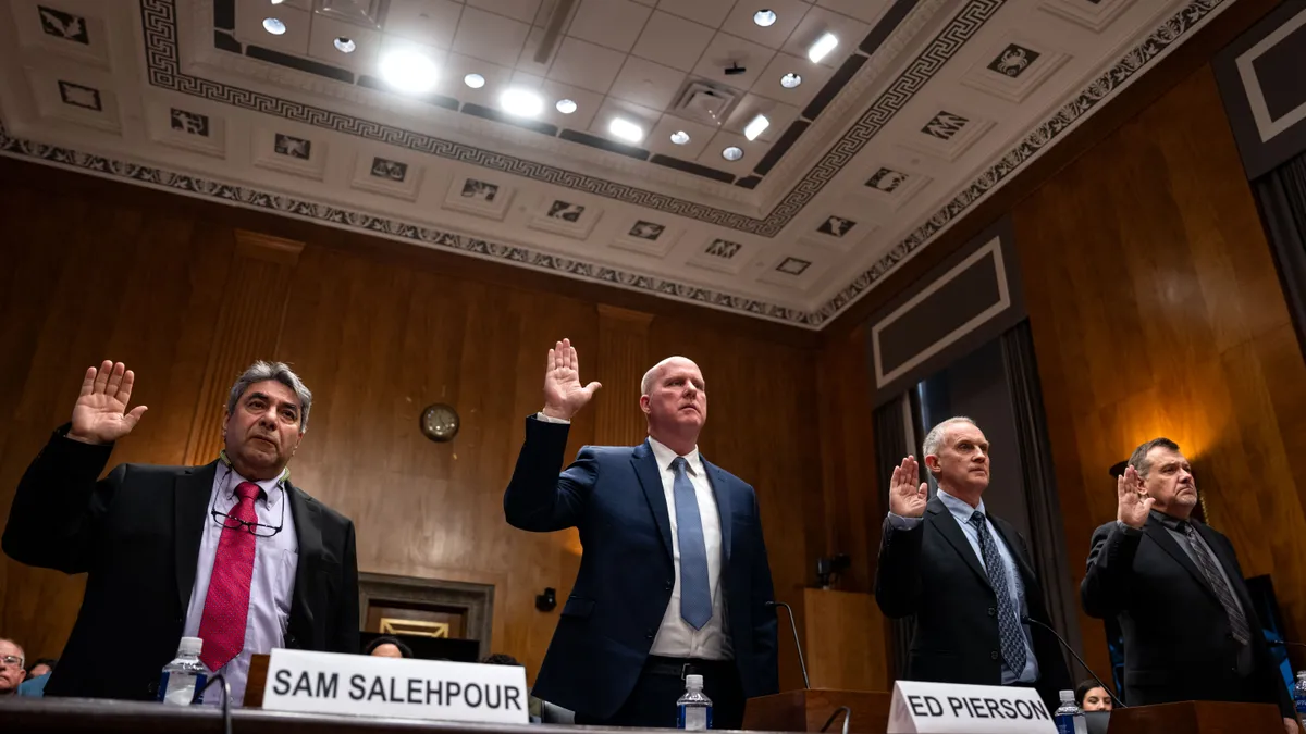 Four people in suits raising their right hand.