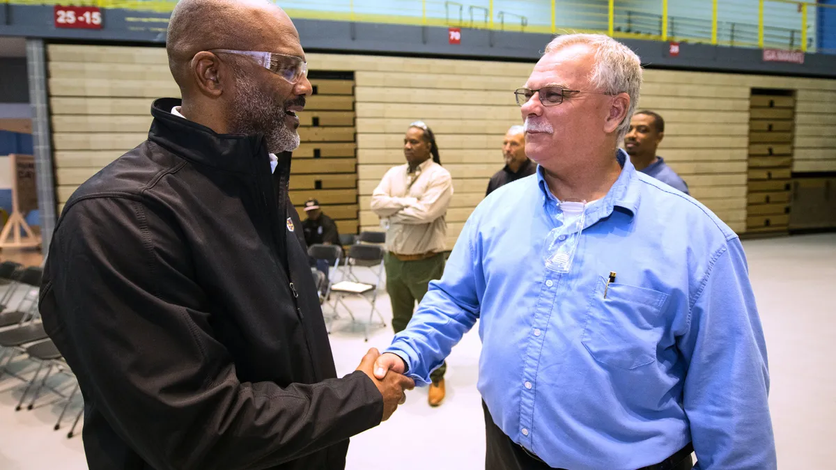 Gerald Johnson and UAW Vice President Mike Booth shake hands at GM's Arlington Assembly plant in June 2023.