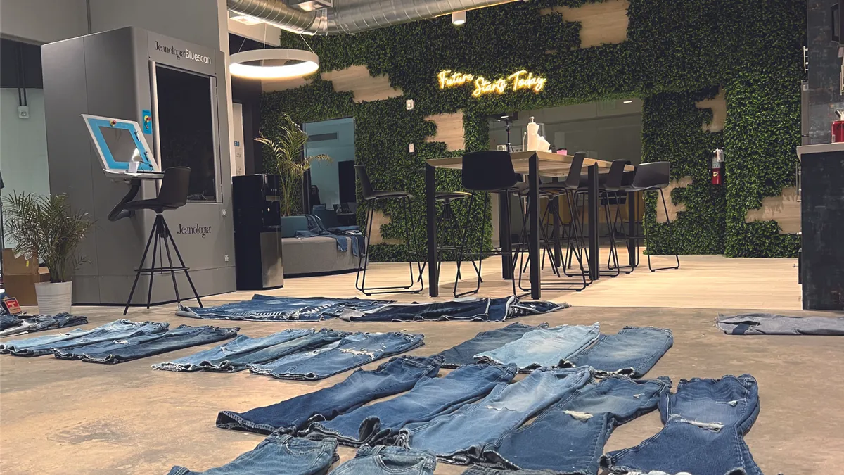 An interior view of Jeanologia's new Miami hub. Multiple pairs of jeans of different cuts and shades are on the ground in an office space.