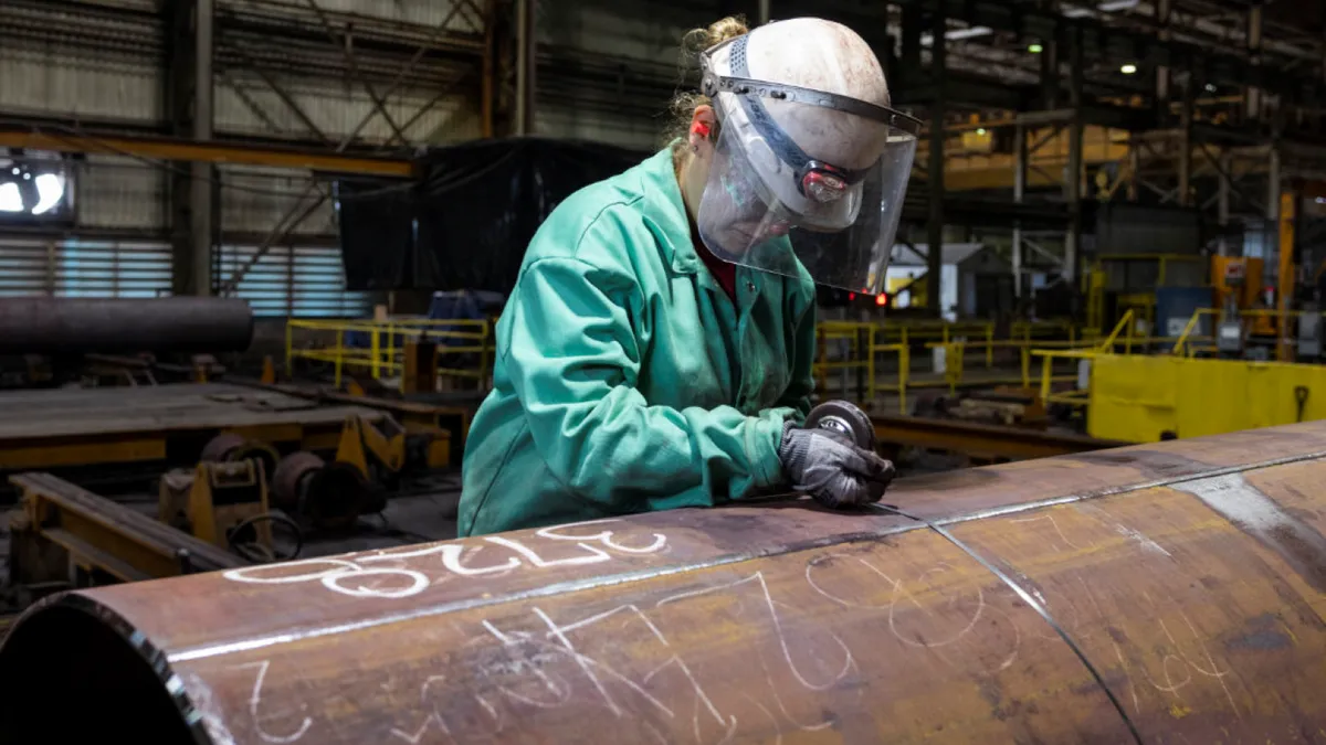 A person wearing personal protective equipment inspecting steel.