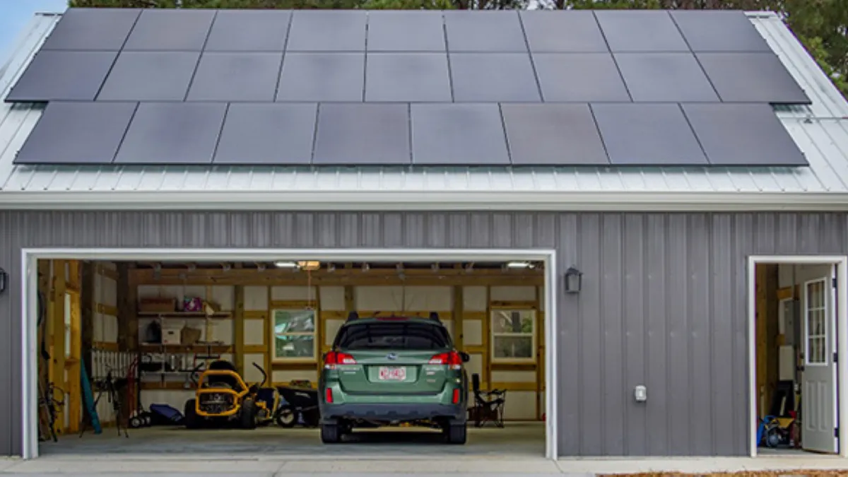 A gray garage building with solar panels on its roof.