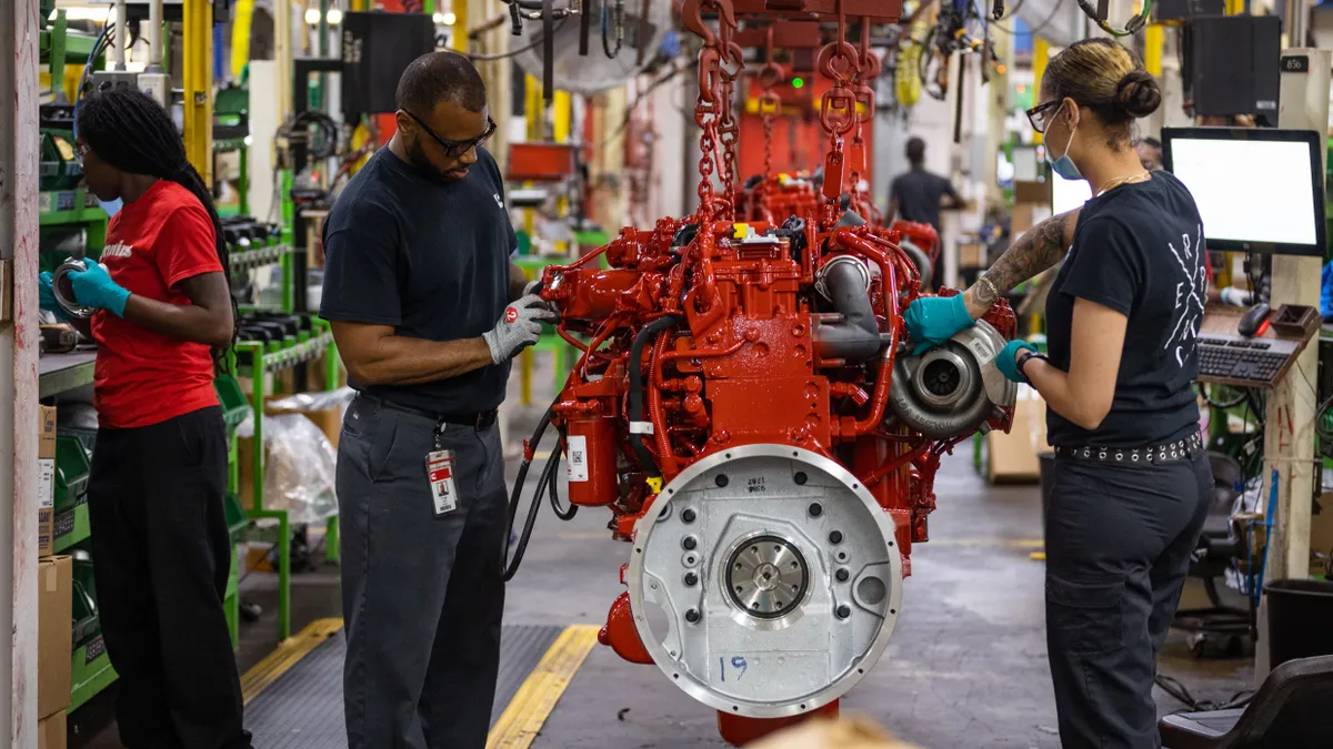 Three employees working in an engine factory.