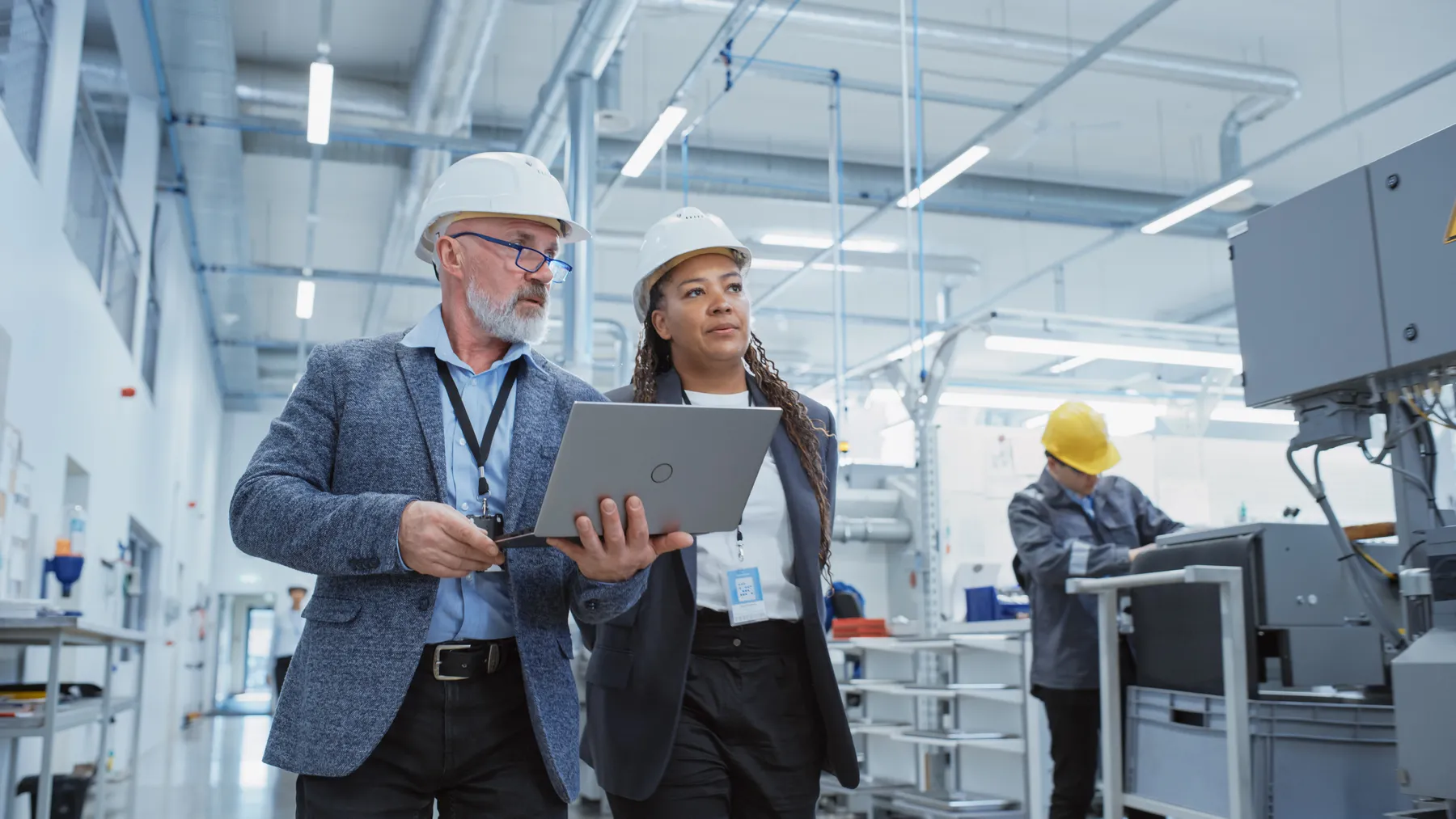 Two professional heavy industry engineers wearing hard hats at factory.