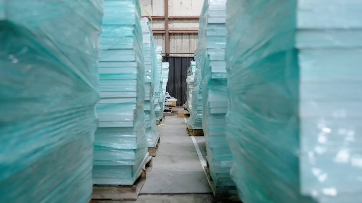 Rows of stacked solar panels in a warehouse.